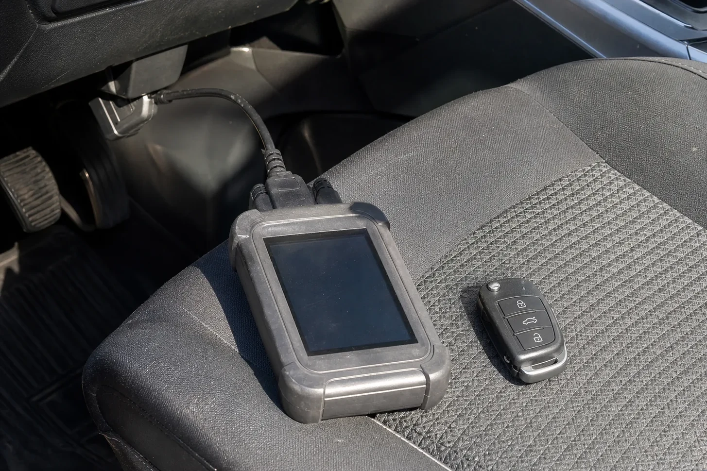 Car key programmer plugged into the OBD port, CA